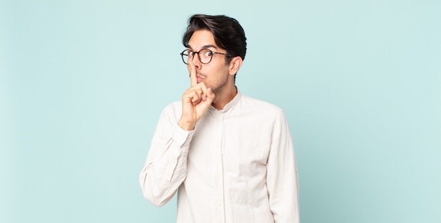 Hispanic handsome man asking for silence and quiet, gesturing with finger in front of mouth, saying shh or keeping a secret