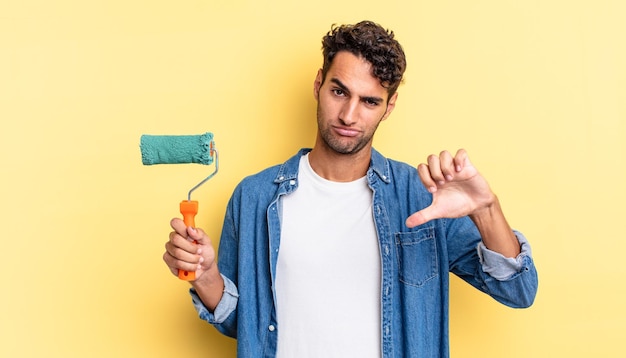 Photo hispanic handsome man feeling cross,showing thumbs down. roller paint concept