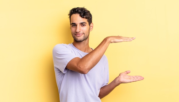 Hispanic handsome man smiling, feeling happy and holding or showing a concept