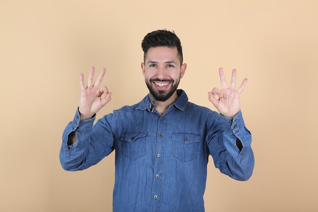 Hispanic latino man makes ok gesture with his hands on yellow background