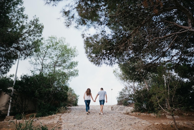 A Hispanic man and brunette woman are strolling in the highland park in Spain