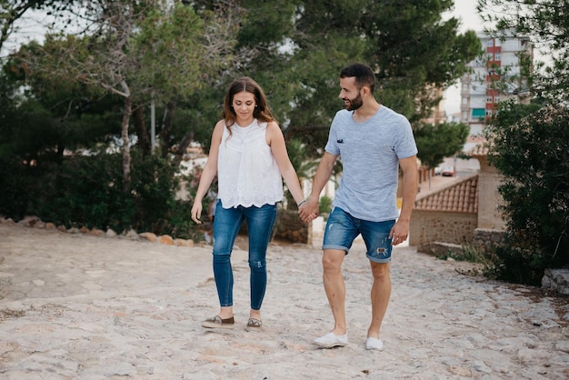 A Hispanic man and brunette woman are strolling in the highland park in Spain