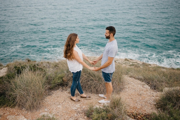 A Hispanic man is hugging his girlfriend in the highland park near sea in Spain