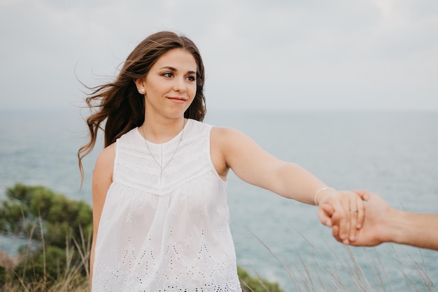 A Hispanic man is hugging his girlfriend in the highland park near sea in Spain