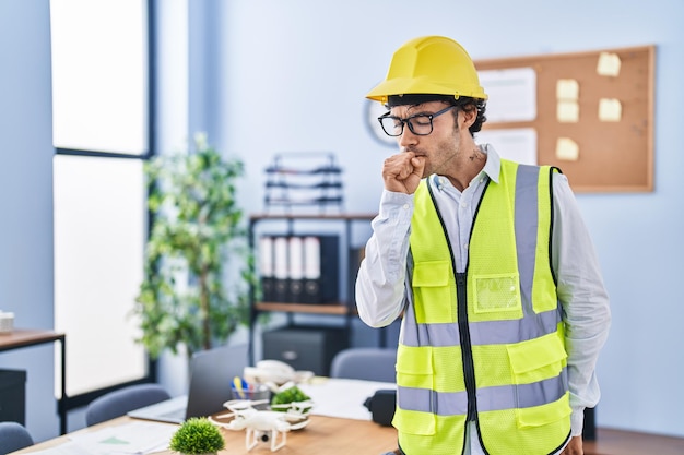 Hispanic man wearing architect hardhat feeling unwell and coughing as symptom for cold or bronchitis. health care concept.