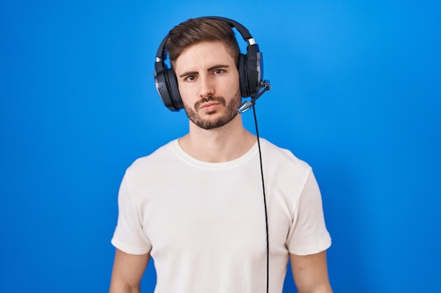 Hispanic man with beard listening to music wearing headphones looking at the camera blowing a kiss on air being lovely and sexy love expression