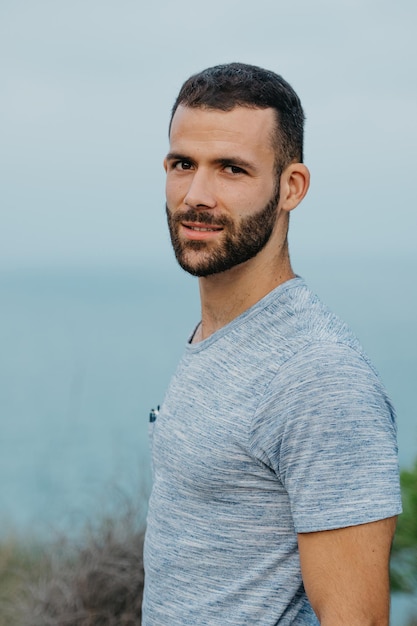 A Hispanic man with a beard near the sea in a highland park in Spain