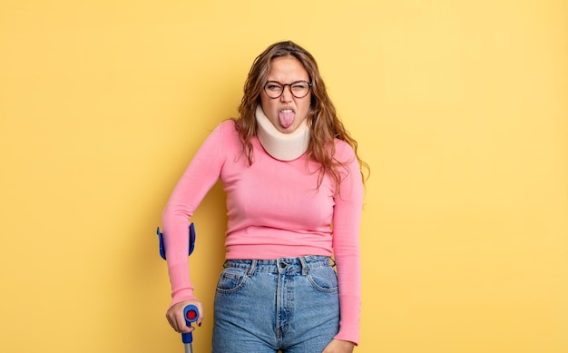 Hispanic pretty woman feeling disgusted and irritated and tongue out. crutch and collar accident