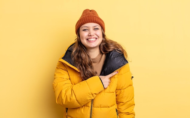 Photo hispanic pretty woman smiling cheerfully feeling happy and pointing to the side winter clothes