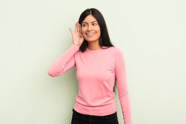 Hispanic pretty woman smiling, looking curiously to the side, trying to listen to gossip or overhearing a secret