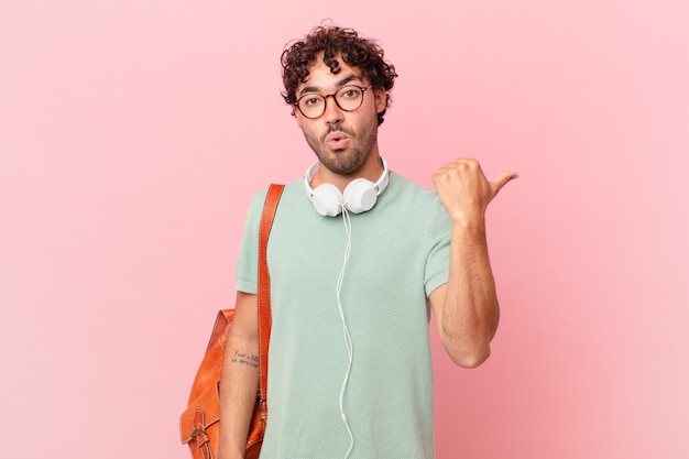 Hispanic student looking astonished in disbelief, pointing at object on the side and saying wow, unbelievable