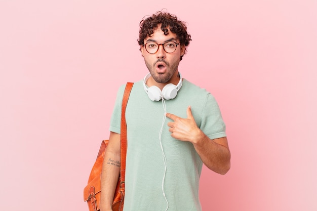 Hispanic student looking shocked and surprised with mouth wide open, pointing to self