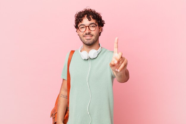 Hispanic student smiling and looking friendly, showing number one or first with hand forward, counting down