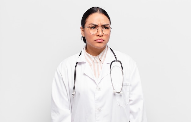 Hispanic woman feeling sad, upset or angry and looking to the side with a negative attitude, frowning in disagreement