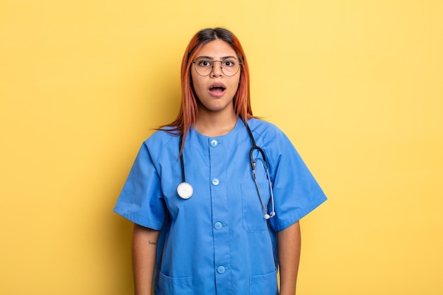 Hispanic woman looking very shocked or surprised nurse concept