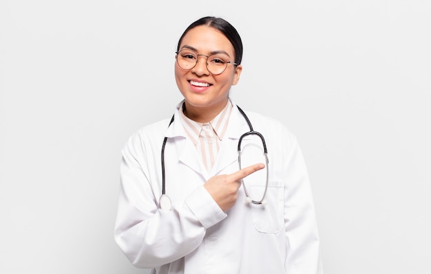 Hispanic woman smiling cheerfully, feeling happy and pointing to the side and upwards, showing object in copy space