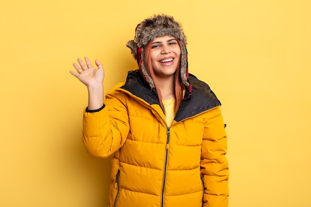 Hispanic woman smiling happily waving hand welcoming and greeting you winter concept