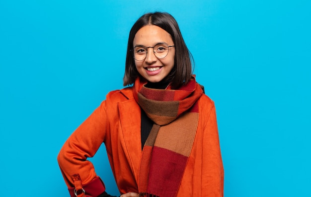 hispanic woman smiling happily with a hand on hip and confident, positive, proud and friendly attitude