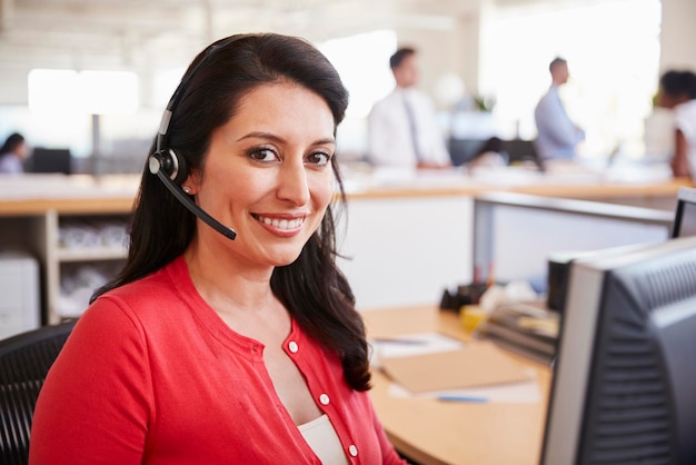 Hispanic woman working in a call centre smiling to camera