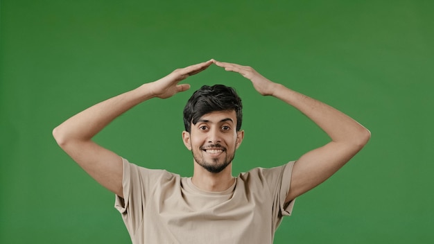 Hispanic young man arabian guy raise hands over head make house roof frame gesture arms feel safe