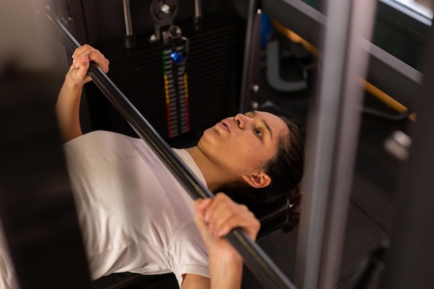 Hispanic young sports woman lifting weights in the gym