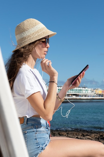 Hispanic young woman listening to music from her mobile phone and using headphones