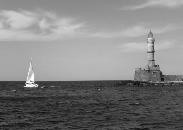 Historic Lighthouse of Old Port of Chania with a Sailing Boat Crete Island Greece in Monochrome