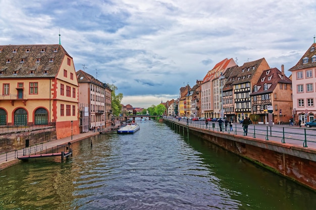 Historical Museum at the waterfront of Ill River and Pont du Corbeau Bridge with Quai des Bateliers Quay in the old town in Strasbourg, Grand East region in France. People on the background