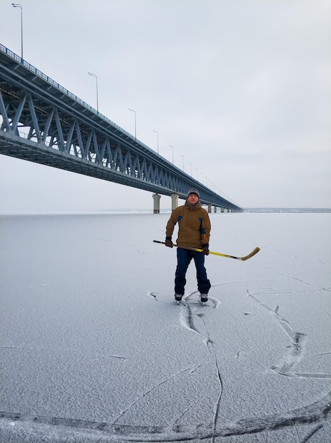 Hockey player on the Volga River the backdrop of a large bridge in Ulyanovsk