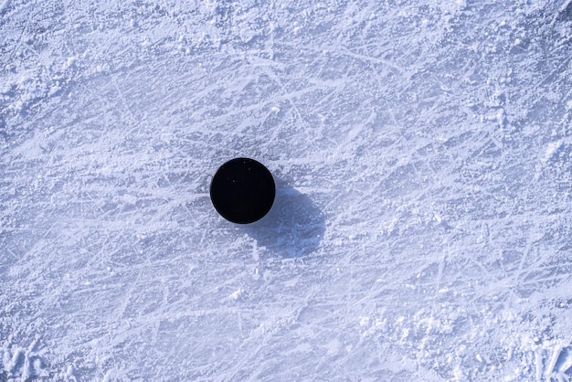 Hockey puck lies on the snow closeup