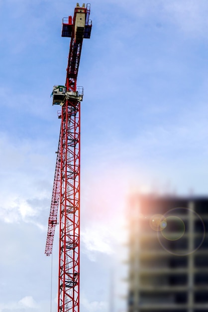 Hoisting crane and Construction crane working building construction on bright blue sky