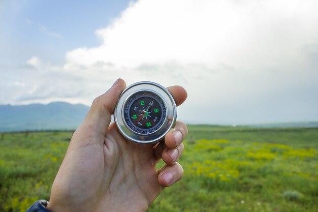 Holding a compass on the background of the field in the evening