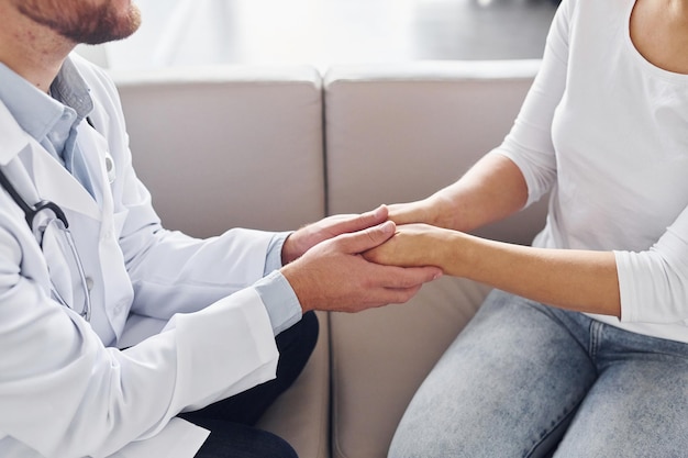 Holding customer by the hands Professional medic in white coat is in the clinic