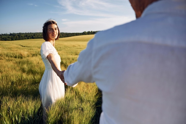 Holding each other by the hands Couple just married Together on the majestic agricultural field at sunny day