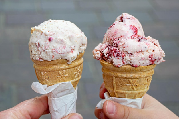 Holding fresh waffle cone with raspberry ice cream