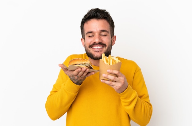 Holding fried chips and cheeseburger over isolated background