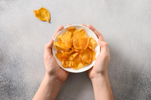 Holding fruits jackfruit chips in white plate