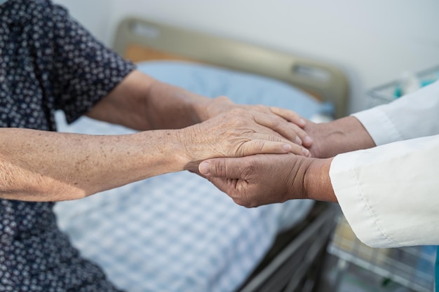 Holding hands Asian senior or elderly old lady woman patient with love care encourage and empathy at nursing hospital ward healthy strong medical concept