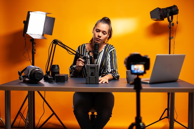 Holding microphone and talking about battery for professional videographer camera