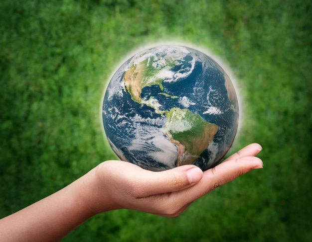 holding a model of the planet on a turquoise background symbolizing Earth Day celebrations