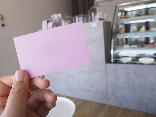 Holding a pink paper with coffee shop background