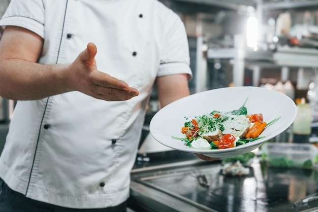 Photo holding and showing finished salad professional chef preparing food in the kitchen