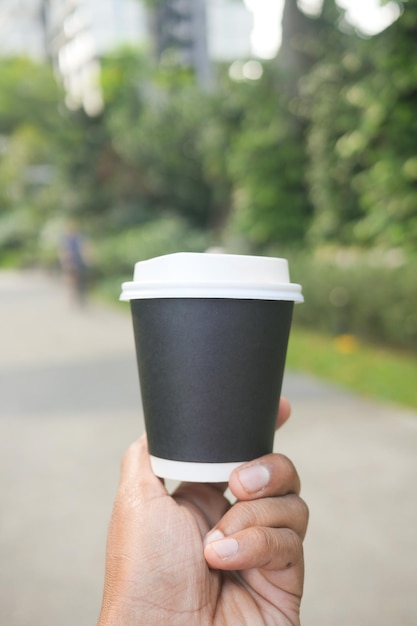 Holding a take away paper coffee cup outdoor