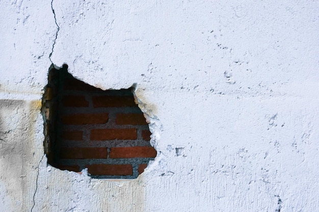 Hole in broken wall and old bricks on white background Large crack on the wall of an old brick house crumbling plaster and broken cracked bricks