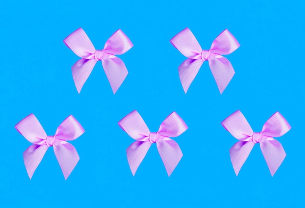 Holiday background Pink bows on the blue background Pattern Flay lay