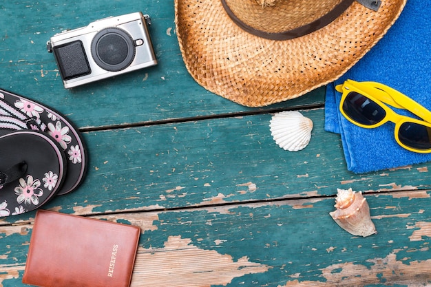 Holiday Concept Vintage wood table with holiday accessories Straw hat sunglasses flip flops shells vintage camera towel and passport