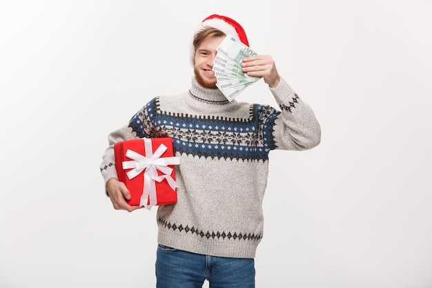 Holiday Concept young beard man holding a christmas gift box and money over white background