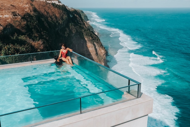 Holiday Couple relaxing in luxury with tropical water villa resort luxurious swimming pool with ocean view Bali , Indonesia