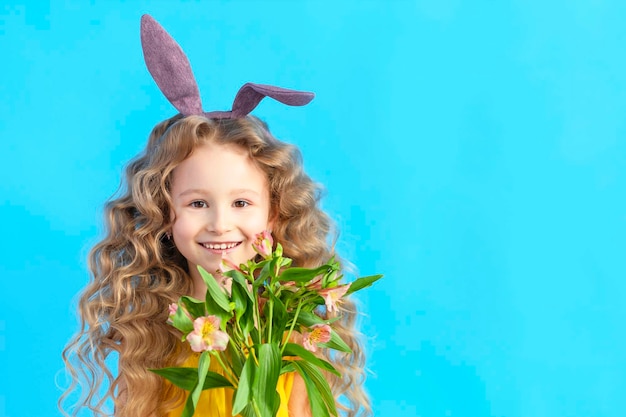 Holiday easter kids smiling girl with rabbit hare bunny ears spring flowers on blue