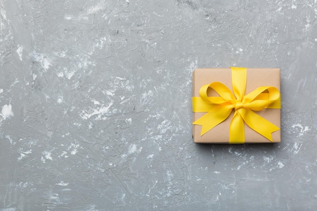 Holiday gift box wrapped in craft paper with colored bow on table background Top view flat lay copy space